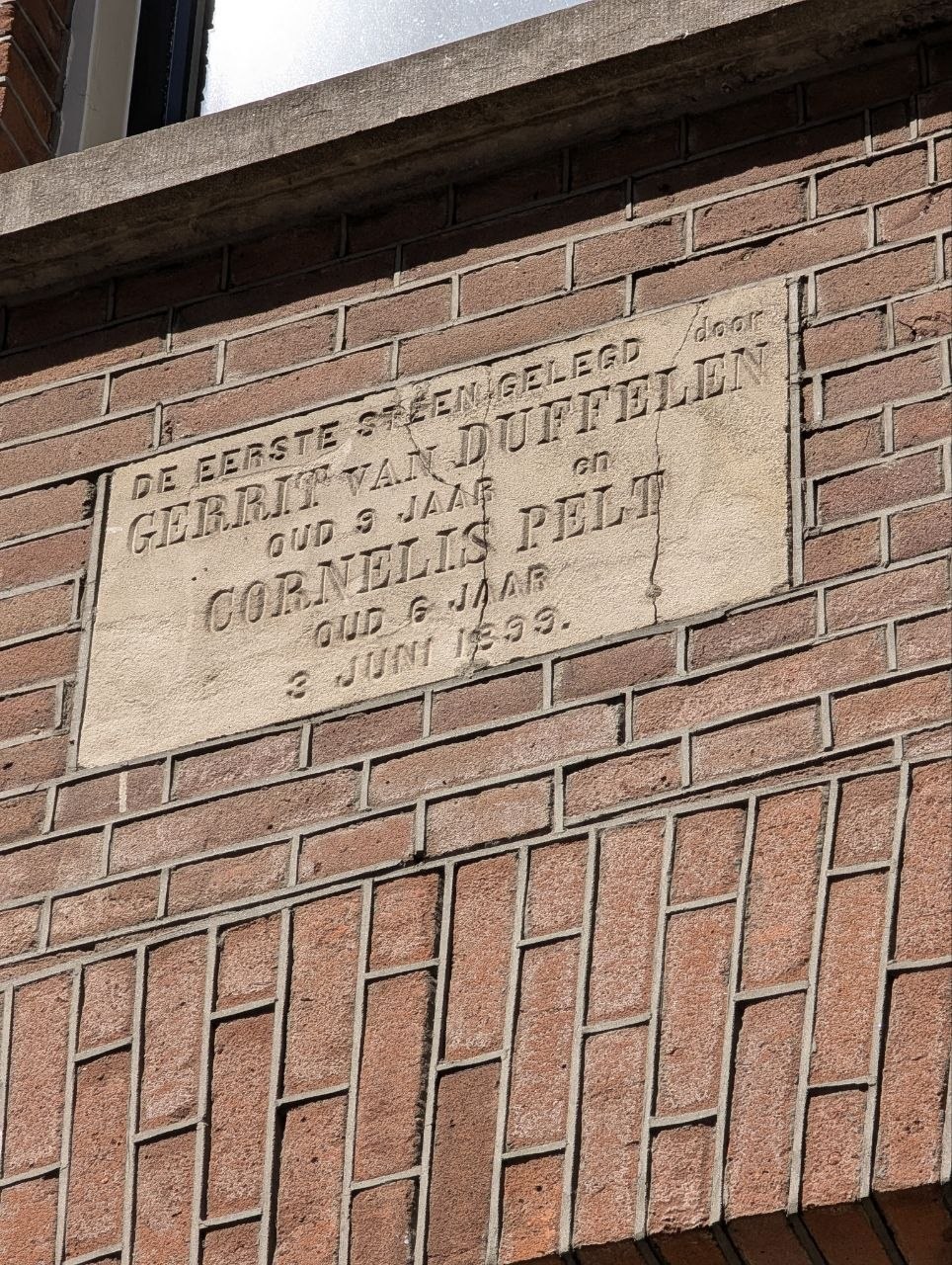 The carved first stone as it stands in the corner wall today, a diagonal crack across one side; photographed by the owner in 2026 — not an image of the 1899 laying.